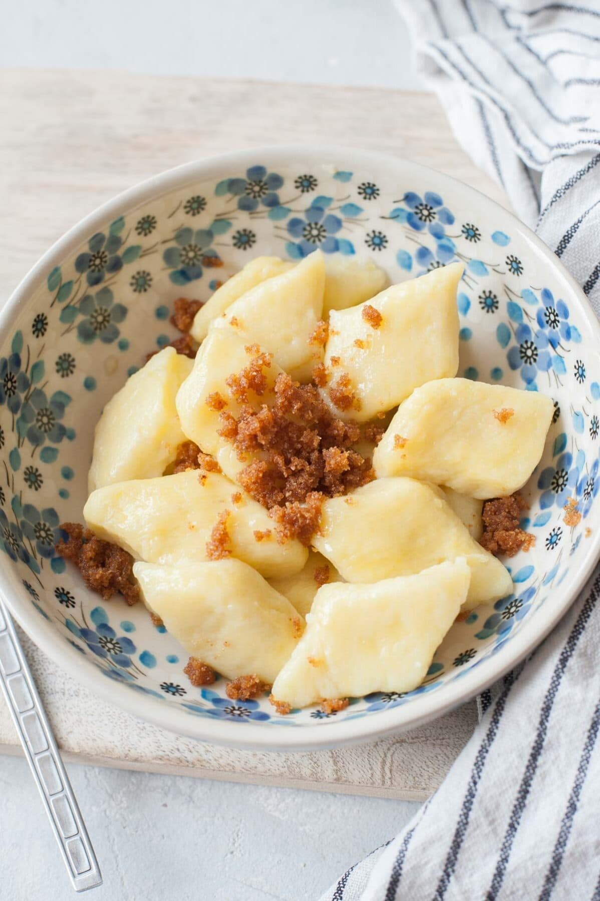 Kopytka with buttered breadcrumbs in a white-blue bowl.