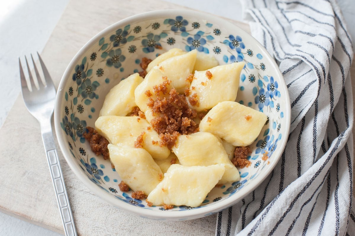 Potato dumplings with buttered breadcrumbs in a white-blue plate.