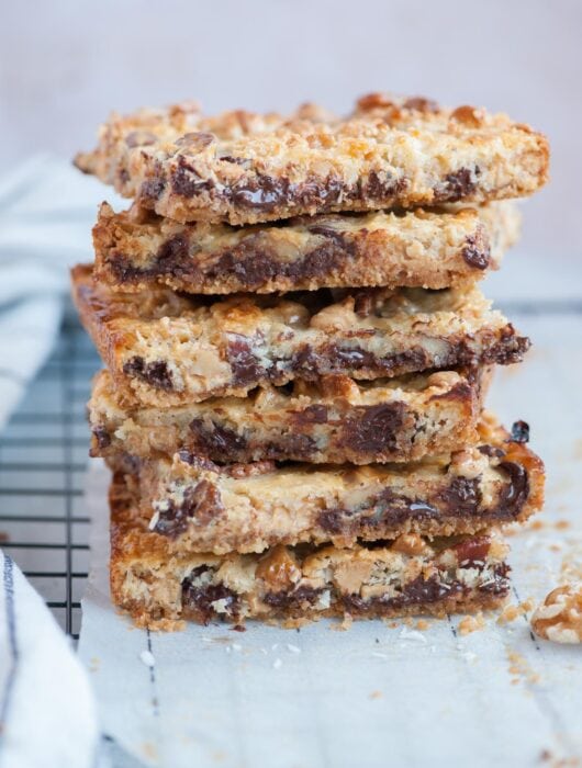 A stack of 7-layer magic bars on a piece of parchment paper.