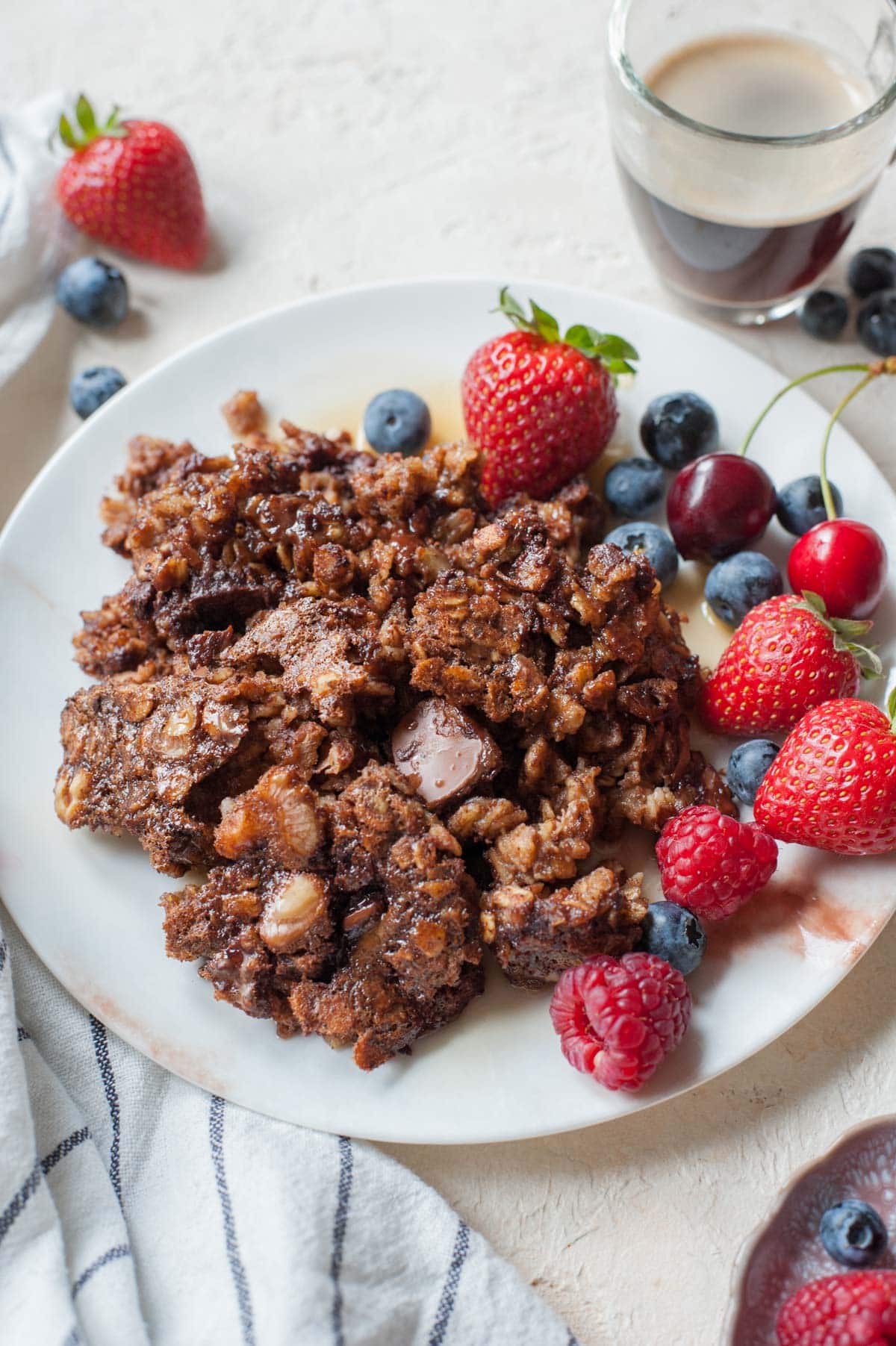 One serving of baked chocolate oatmeal served with fresh berries on a white plate.