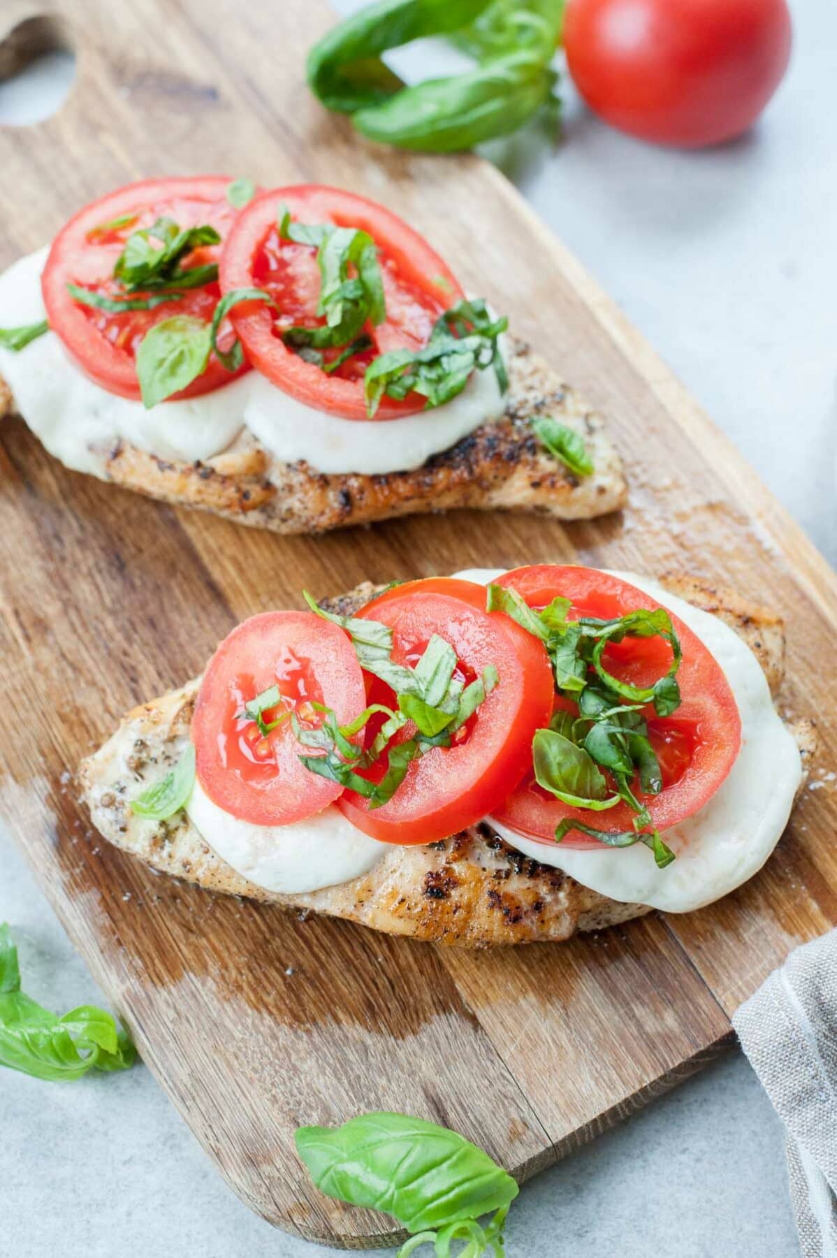 Caprese chicken on a wooden board.