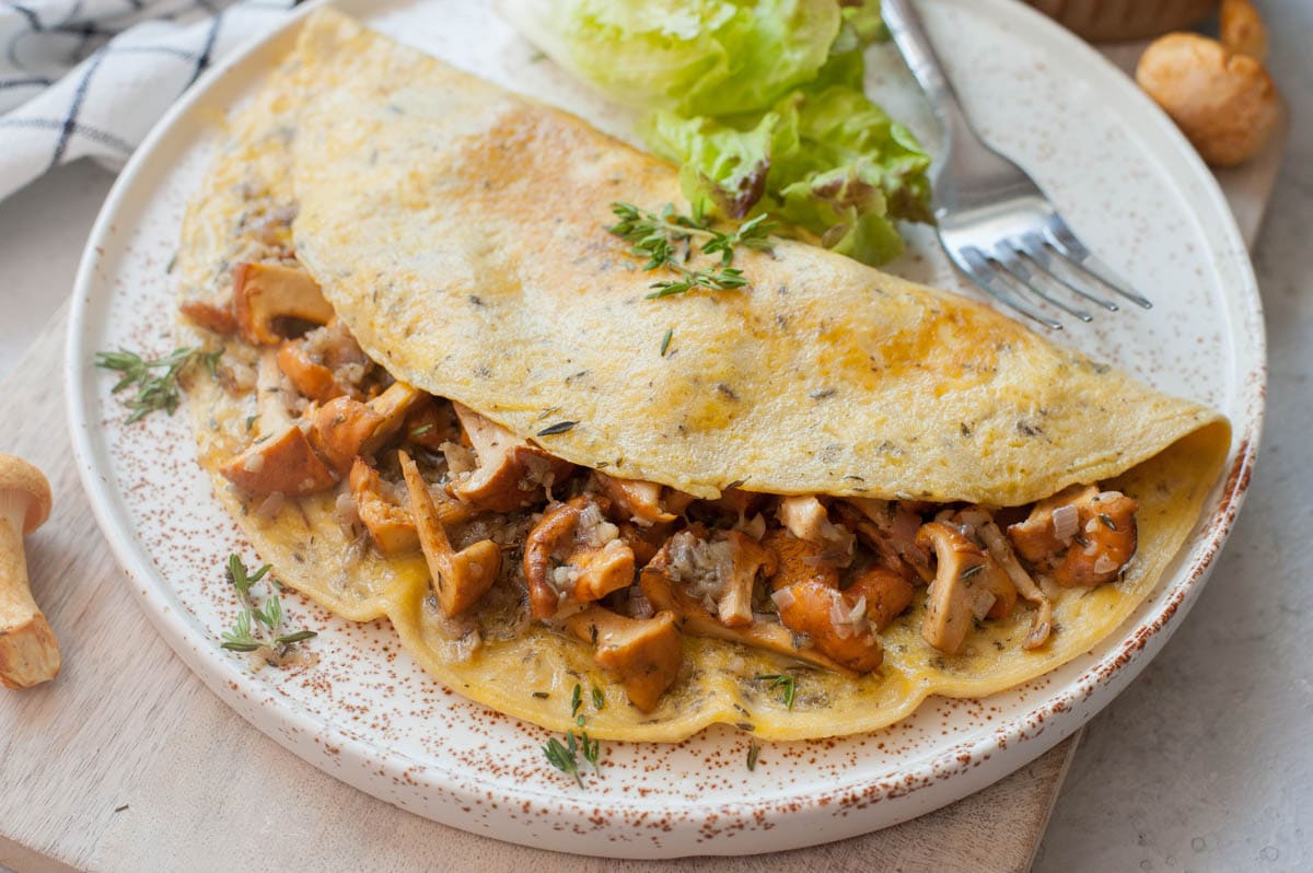 Chanterelle mushroom omelet on a white plate and chopping board.