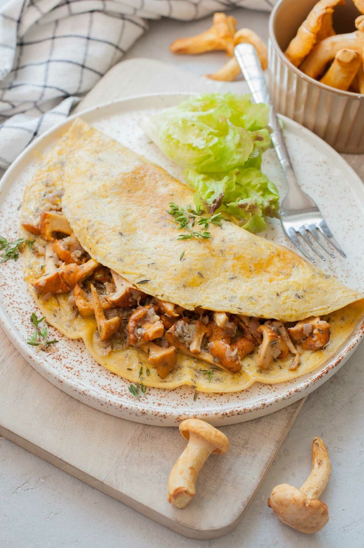 Chanterelle mushroom omelette on a white plate and chopping board.