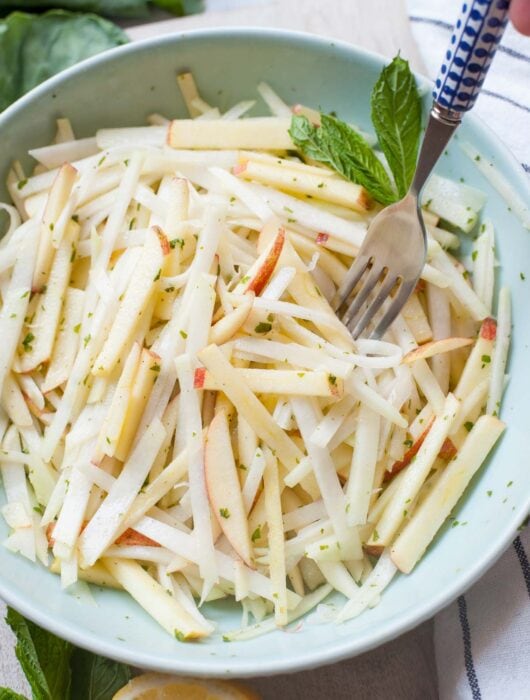 Kohlrabi apple slaw on a green bowl.