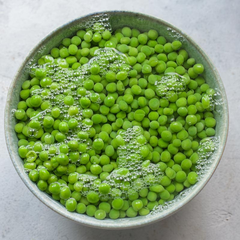 Peas with boiling water in a bowl.