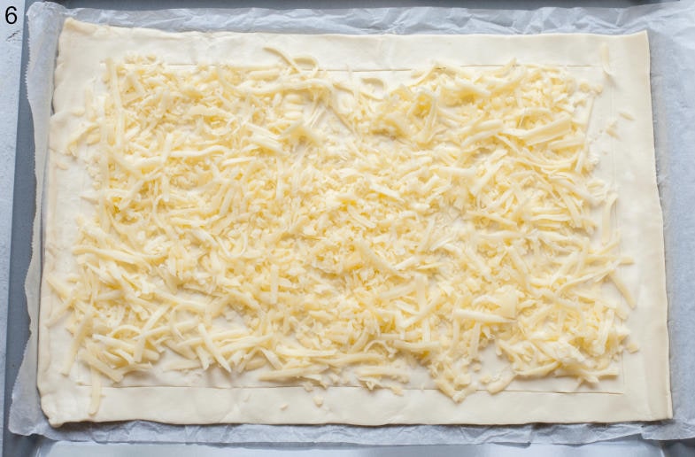 Shredded cheese on a puff pastry sheet.