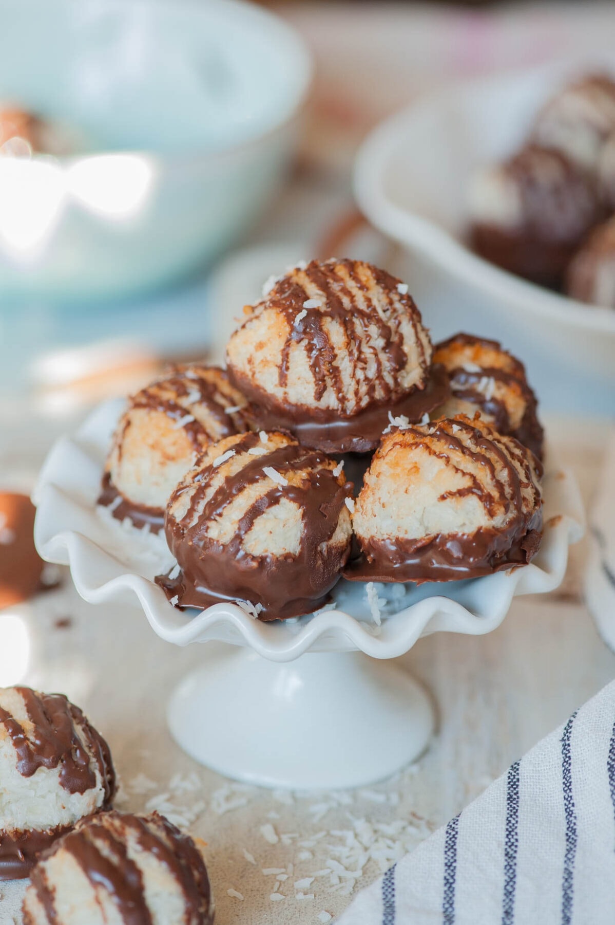 Chocolate dipped coconut macaroons on a white cookie stand.