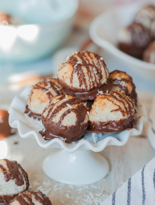 Chocolate-dipped coconut macaroons on a white cookie stand.