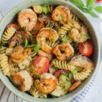 Shrimp pesto pasta in a green bowl.