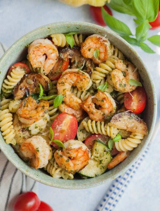 Shrimp pesto pasta in a green bowl.