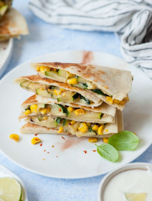 A stack of zucchini quesadillas on a white plate.