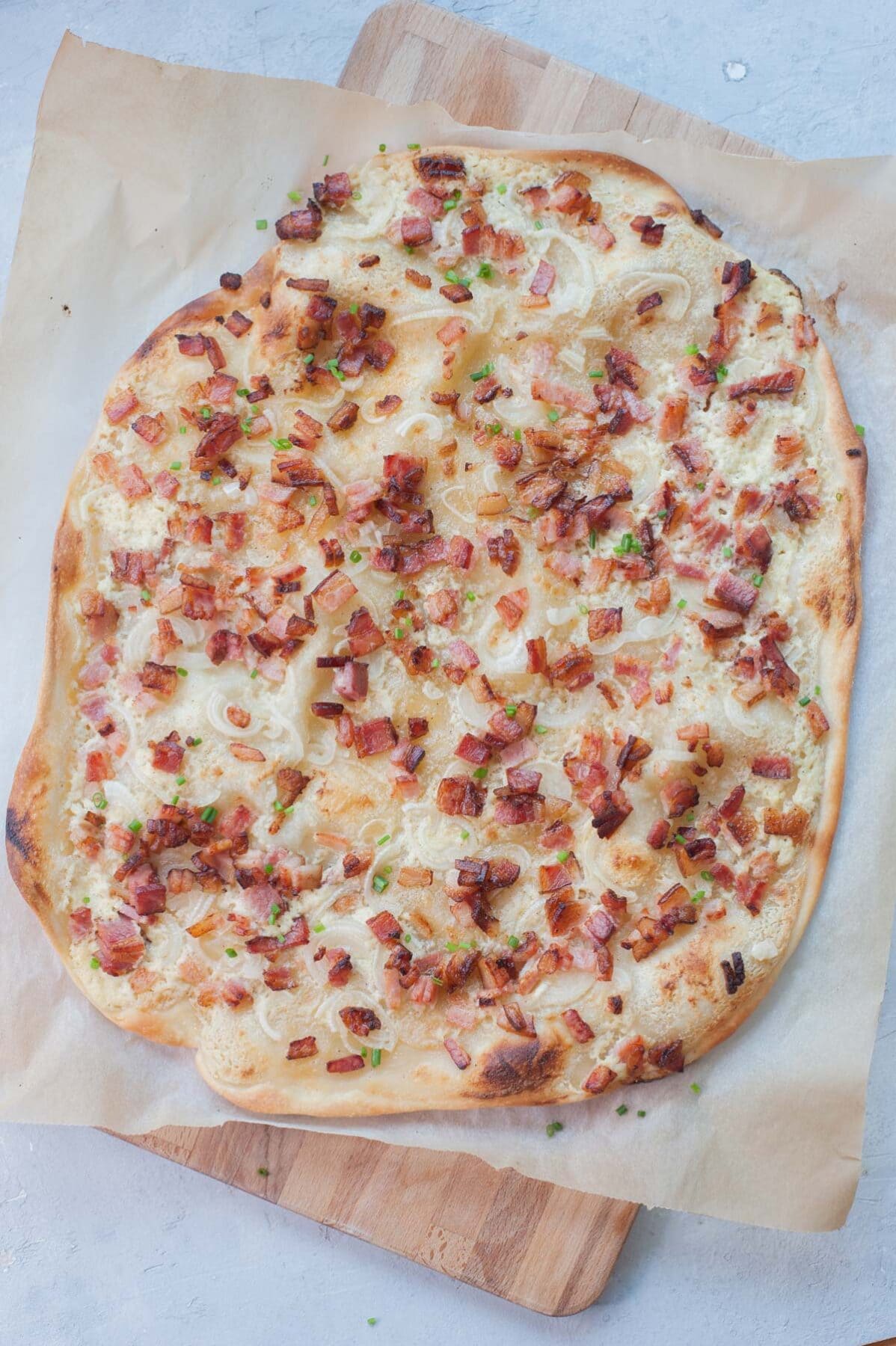 Flammkuchen on a piece of parchment paper.