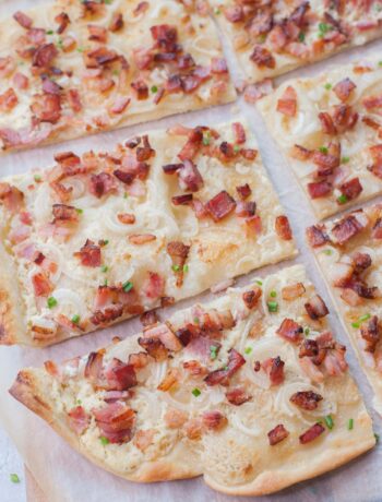 Flammkuchen cut into squares on a piece of parchment paper.