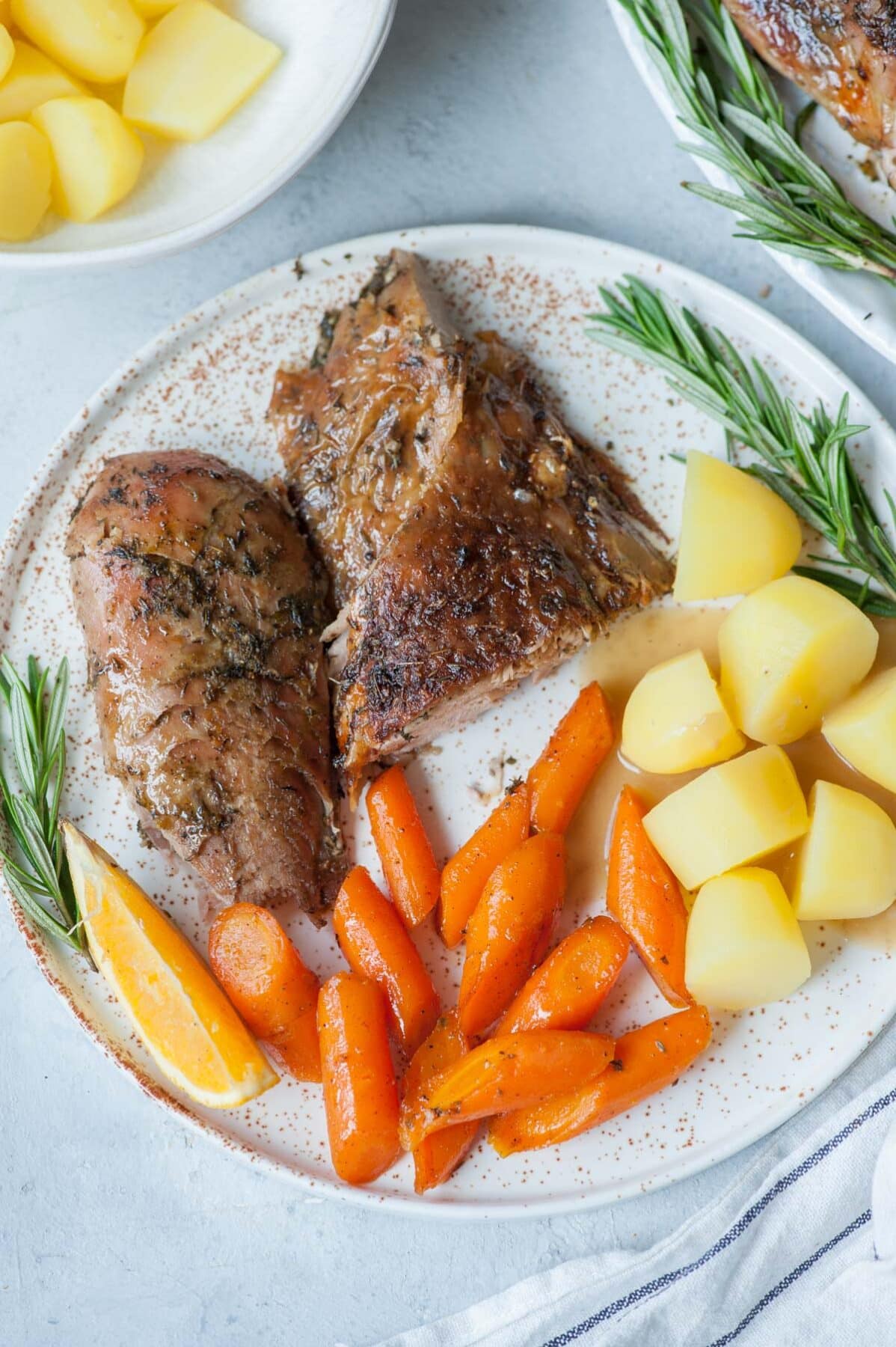 Roasted turkey leg on a white plate with glazed carrots, potatoes and gravy.