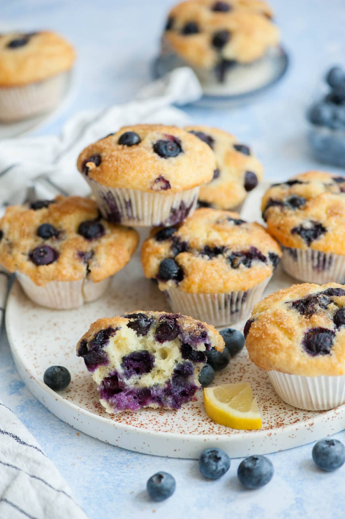 Blueberry yogurt muffins on a white plate with one muffin cut in half.