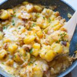 Potato egg scramble with ham and cheese in a pan.