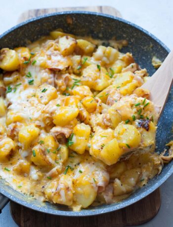 Potato egg scramble with ham and cheese in a pan.