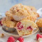 Raspberry muffins on a white plate. One muffin cut in half.