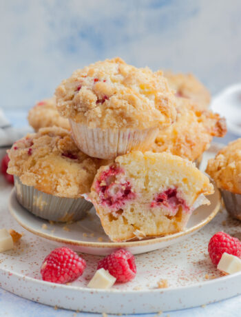 Raspberry muffins on a white plate. One muffin cut in half.