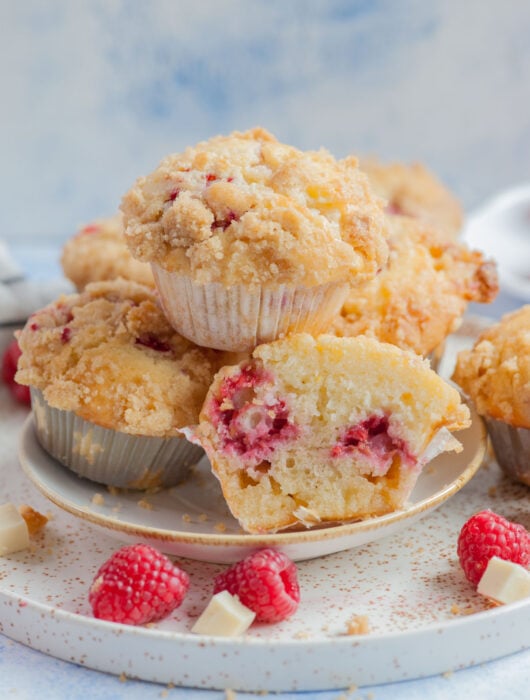 Raspberry muffins on a white plate. One muffin cut in half.