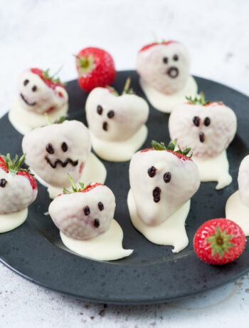 Strawberry ghosts on a black plate.