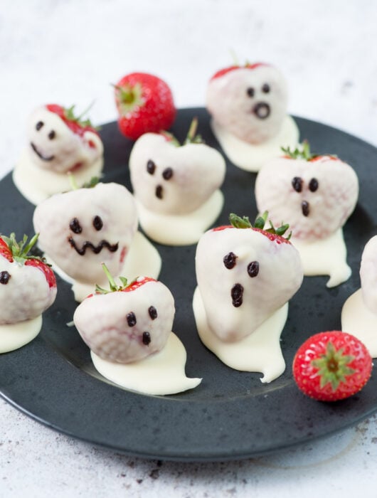 Strawberry ghosts on a black plate.