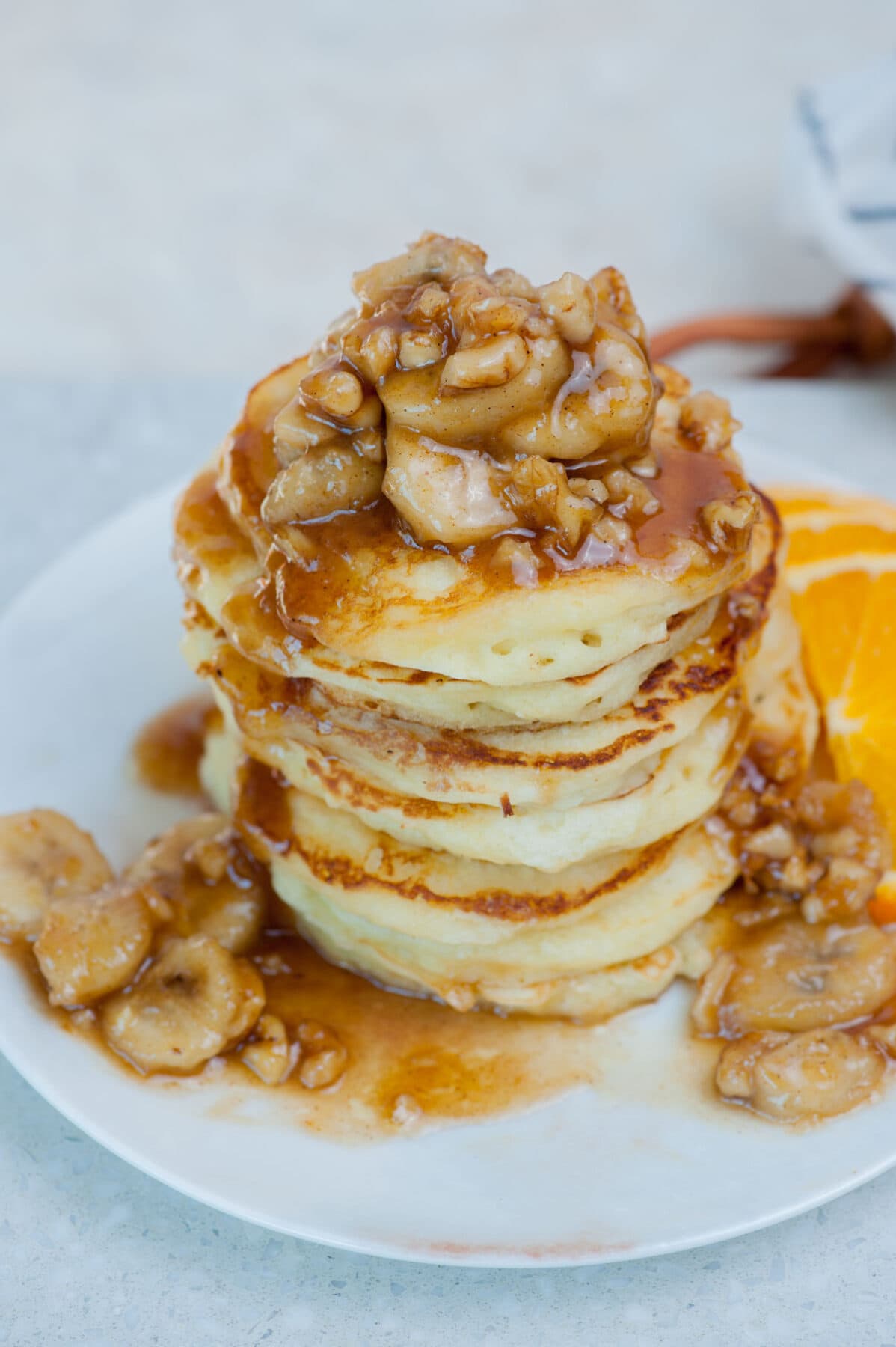 A stack of banana foster pancakes on a white plate.