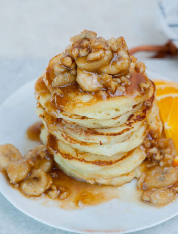 A stack of bananas foster pancakes on a white plate.