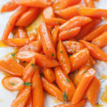 Honey glazed carrots on a white plate.