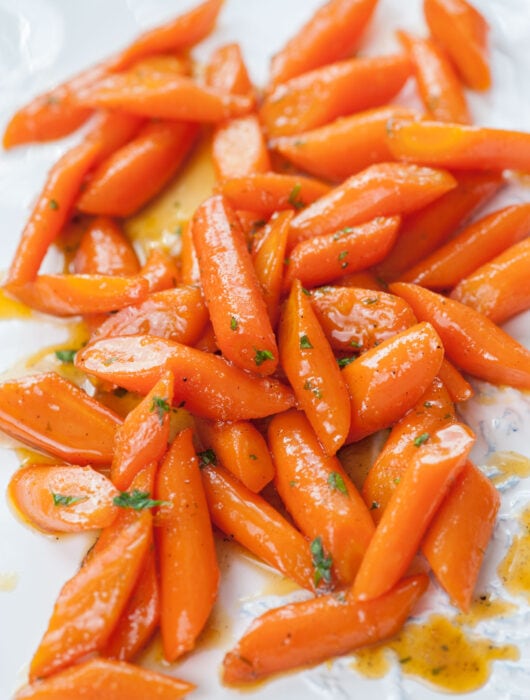 Honey glazed carrots on a white plate.