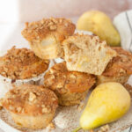 Pear muffins, walnuts, and pear on a white plate.