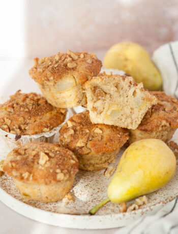 Pear muffins, walnuts, and pear on a white plate.