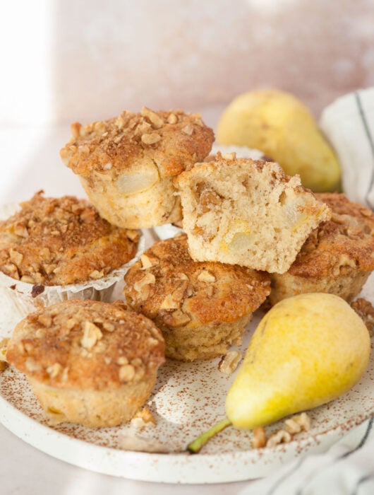 Pear muffins, walnuts, and pear on a white plate.