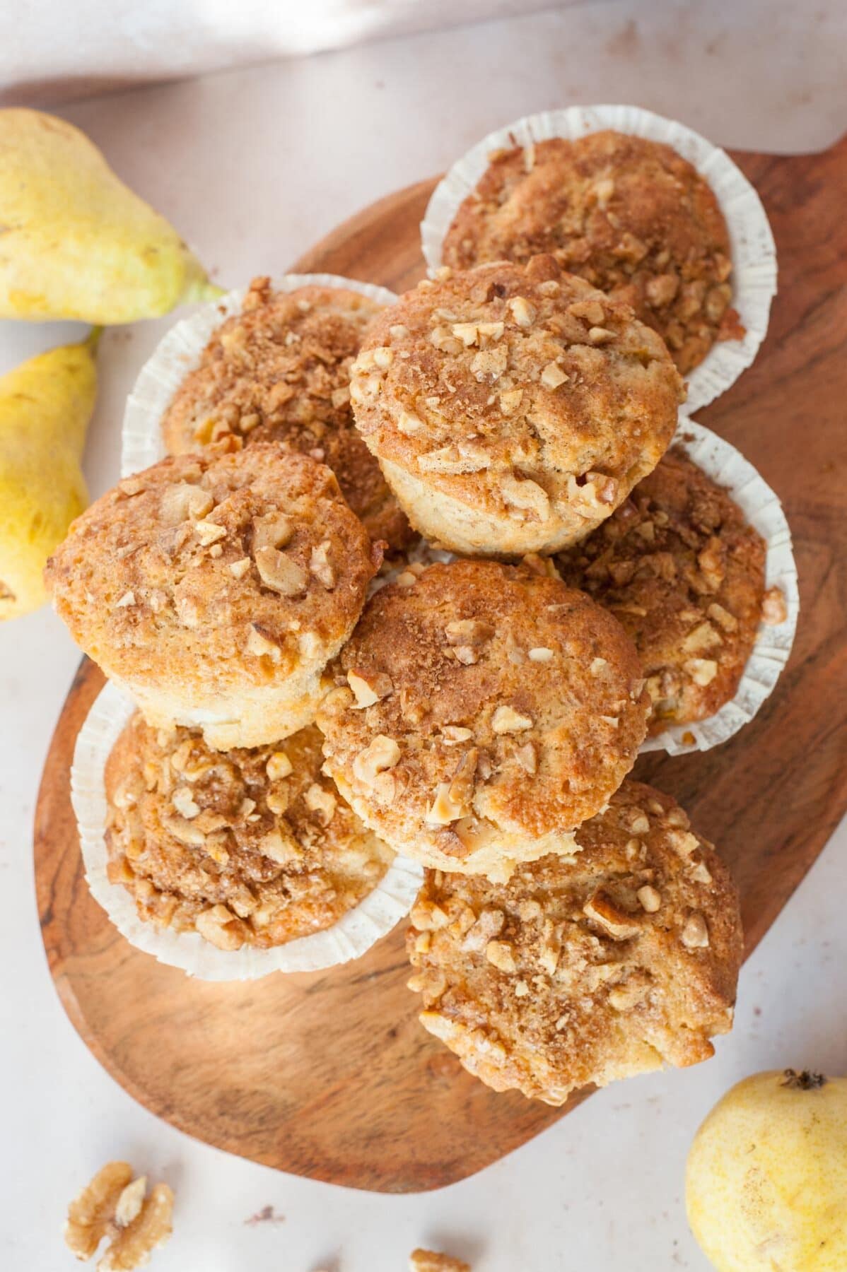 Pear muffins on a wooden board. Walnuts and pears in the background.