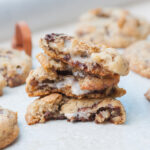 Stacked s'mores cookies torn in half on a light grey background.