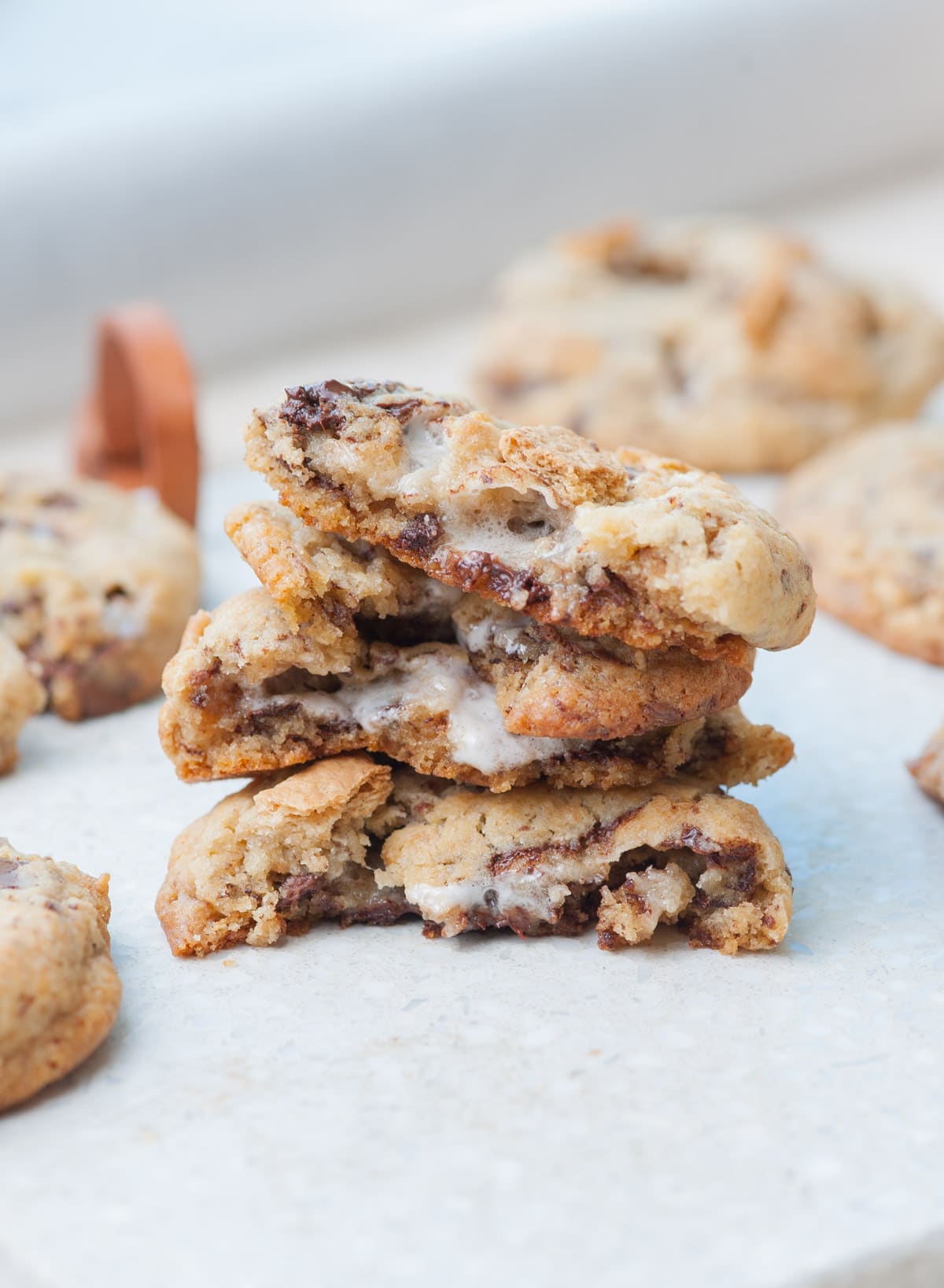 Stacked s'mores cookies torn in half on a light grey background.