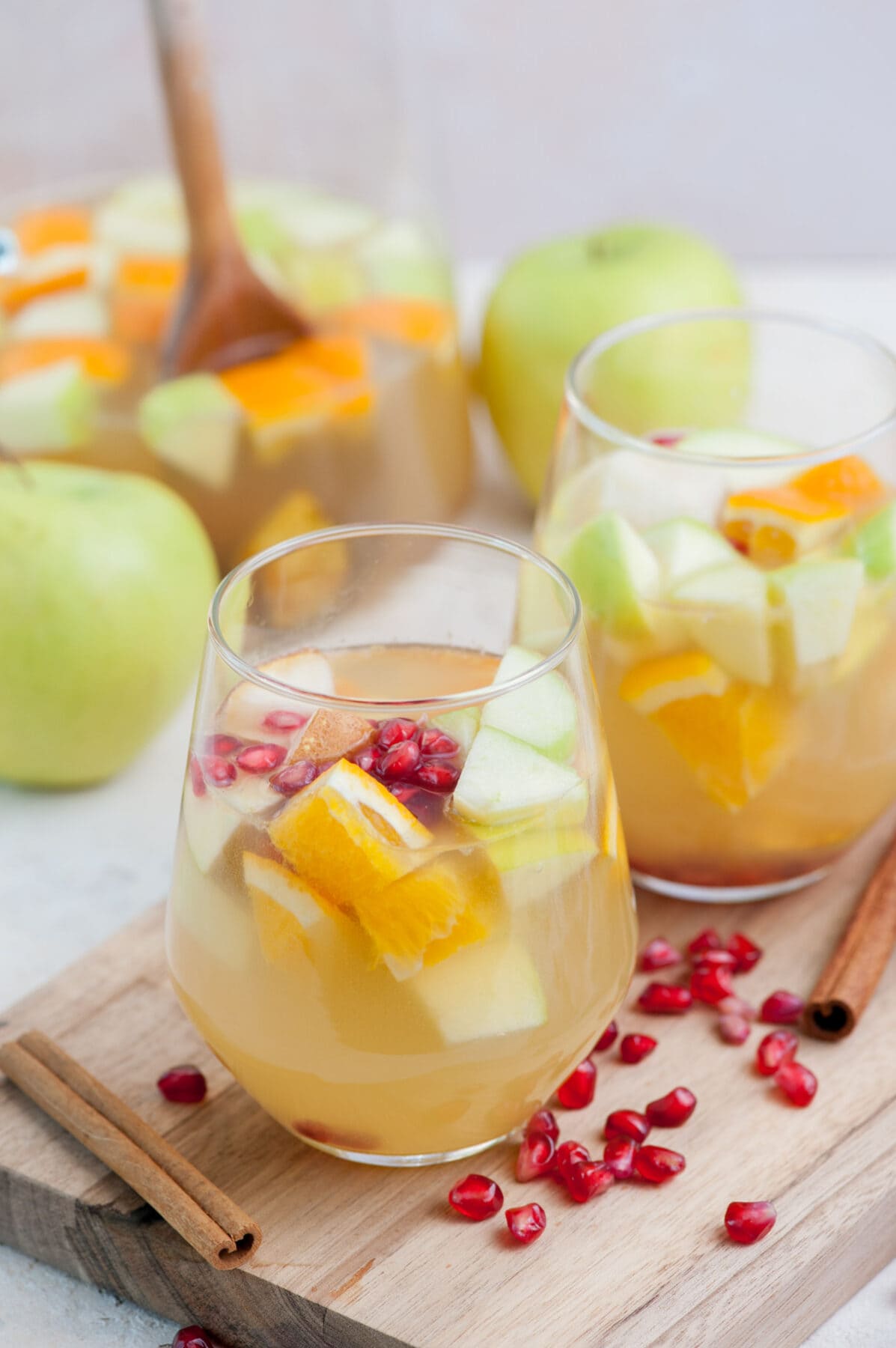 Two glasses with apple cider sangria on a wooden board.