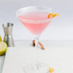 Cosmopolitan cocktail in a martini glass garnished with an orange twist.