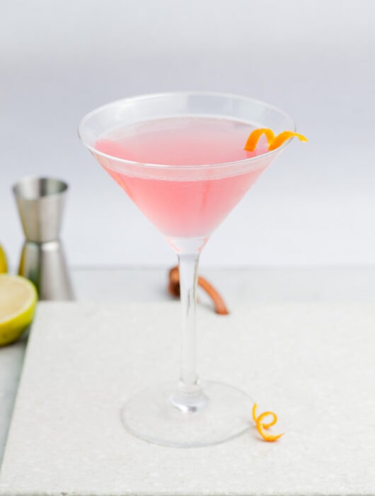 Cosmopolitan cocktail in a martini glass garnished with an orange twist.