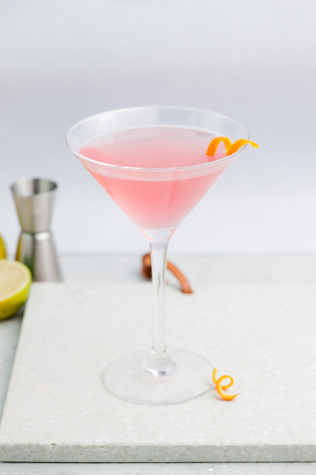 Cosmopolitan cocktail in a martini glass garnished with an orange twist.