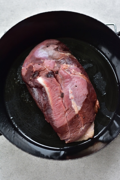 Duck breast is being pan-fried in a black pan.