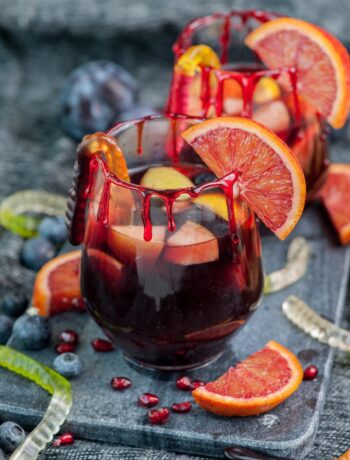 Two glasses with Halloween sangria garnished with blood orange slices.