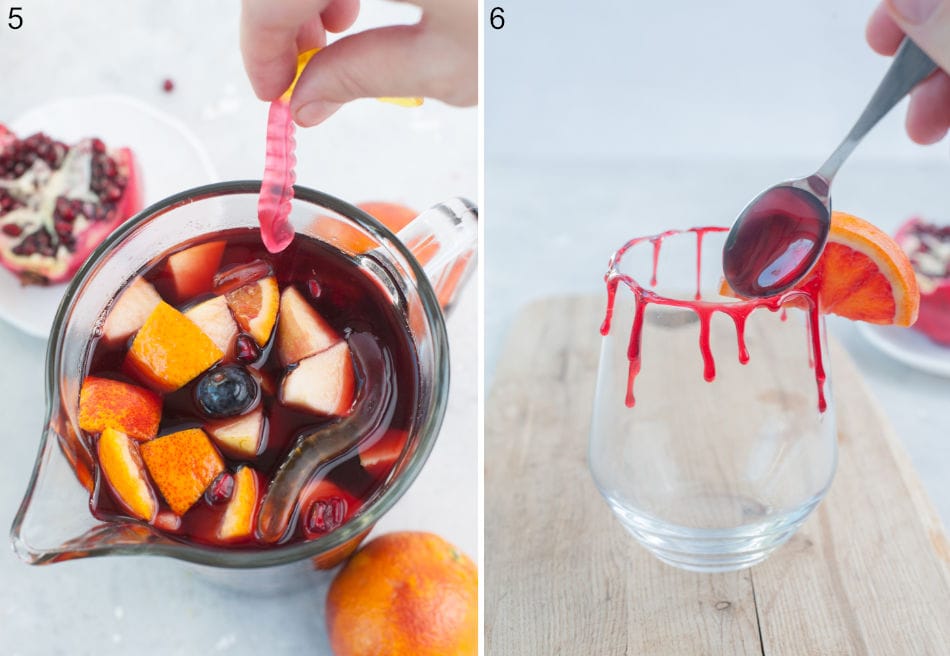 Gummy worms are being added into a sangria in a pitcher. Grenadine syrup is being poured over a rim of the glass.