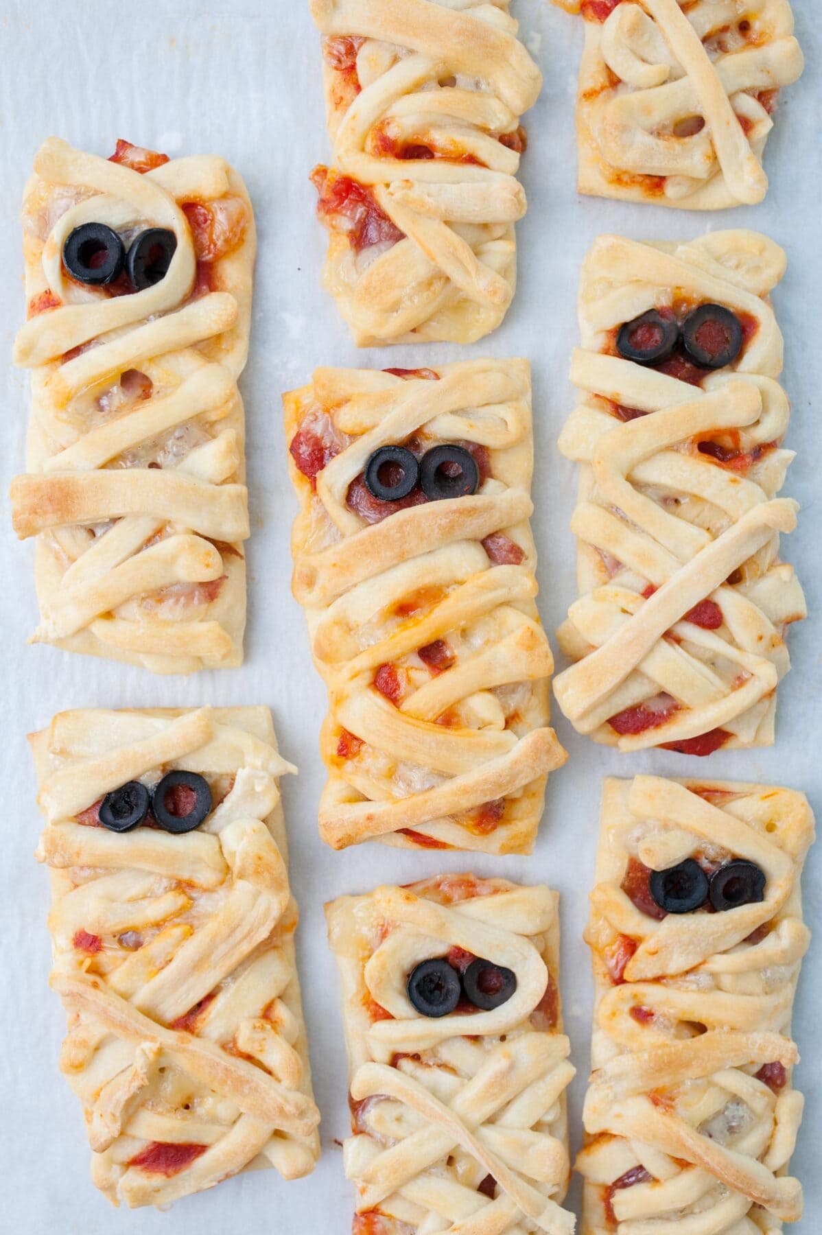 Pizza mummies on a piece of parchment paper.