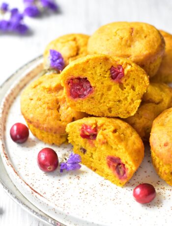 Pumpkin cranberry muffins on a white plate. Two muffins cut in half.