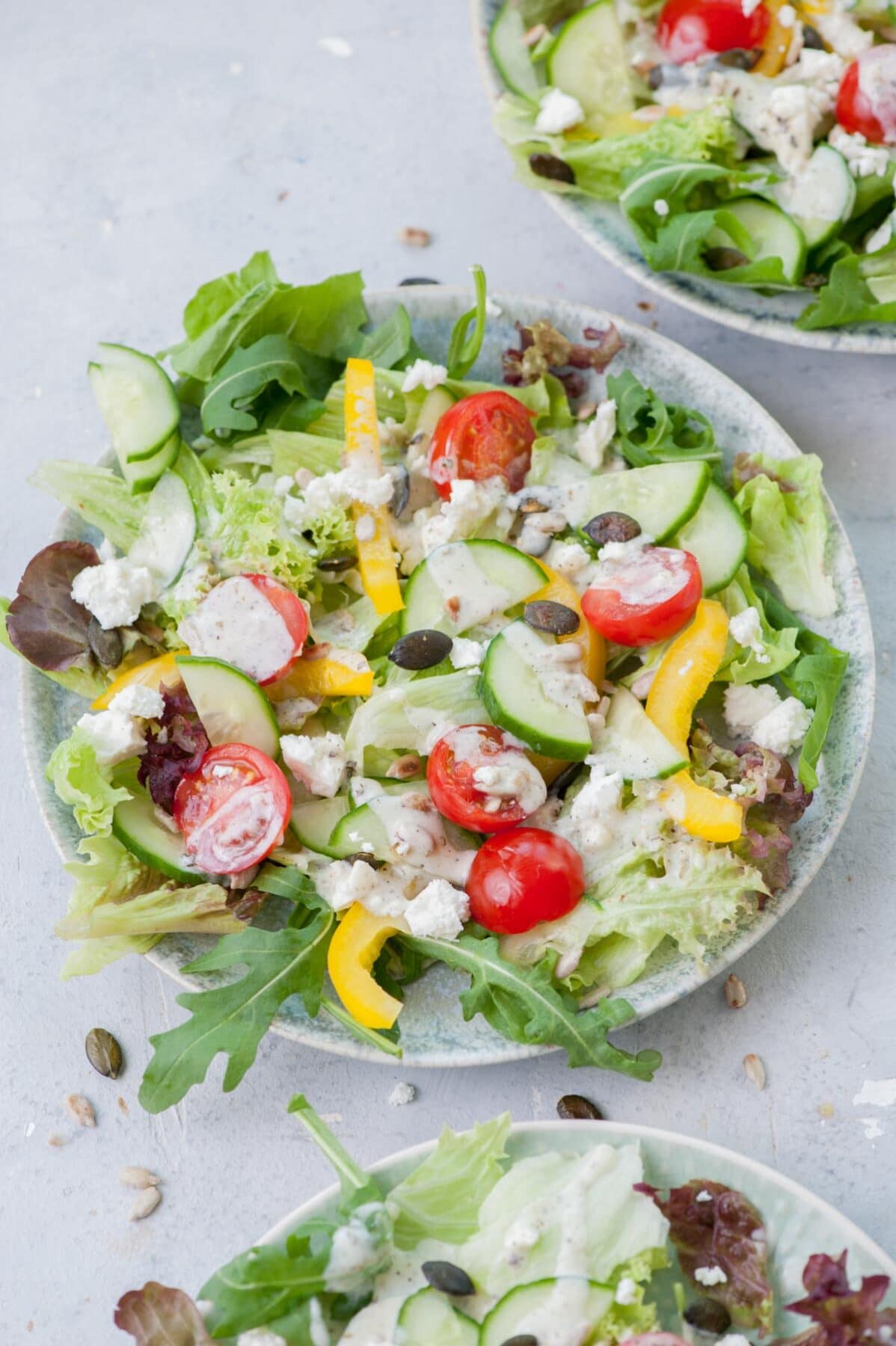 Three plates with salad with yogurt dressing.