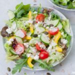 Salad with yogurt dressing on a green plate.