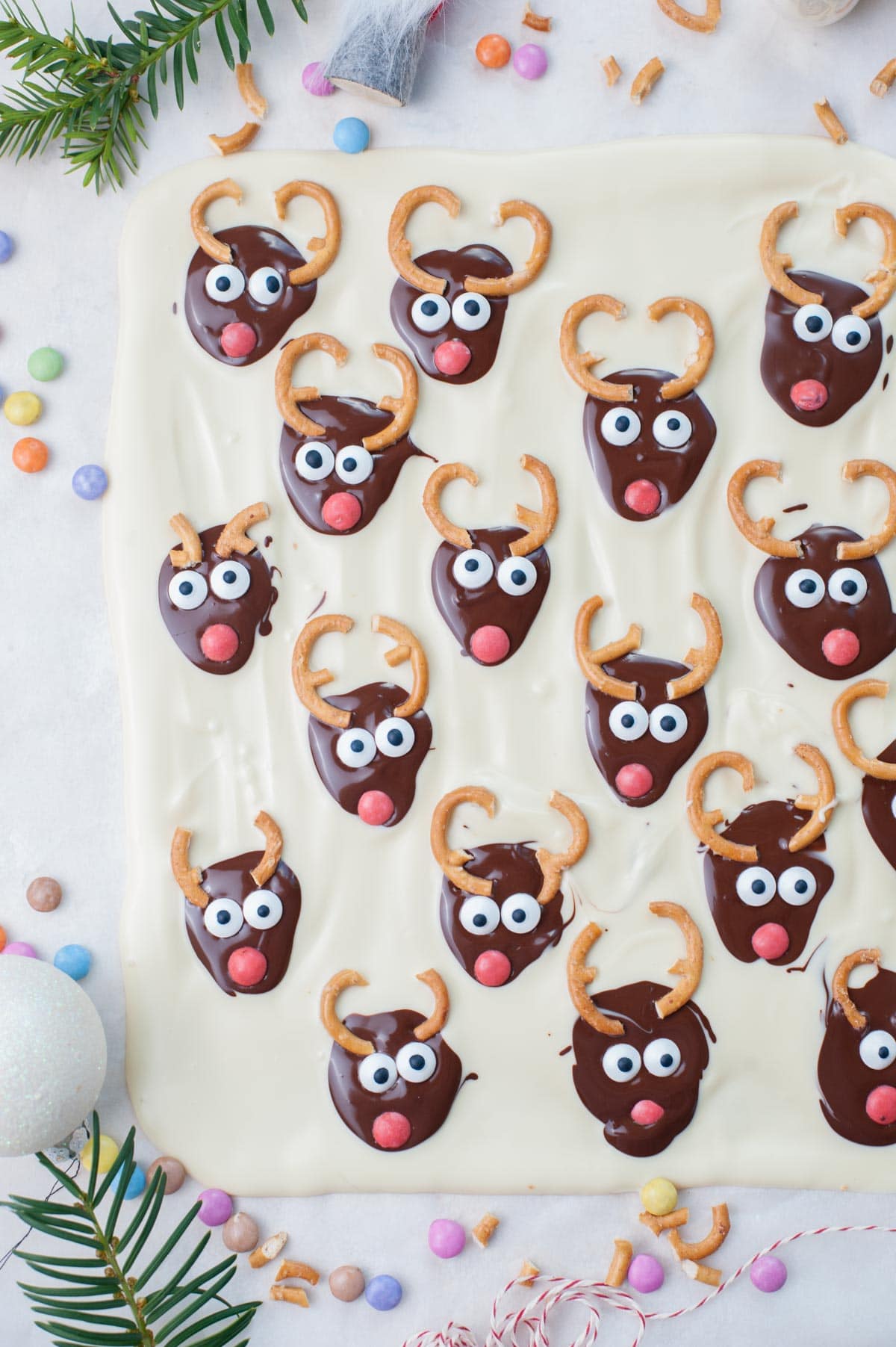 Christmas bark with chocolate reindeer faces on a piece of parchment paper.