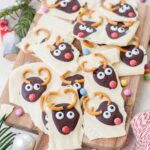 Christmas chocolate bark broken up into pieces on a wooden board.