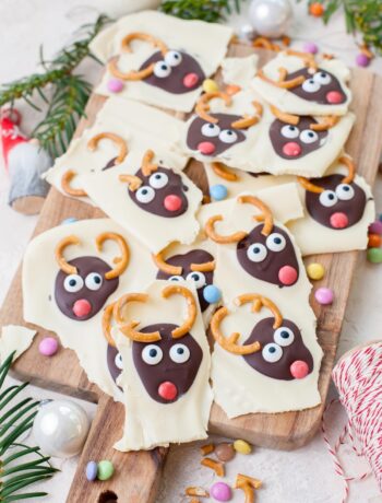 Christmas chocolate bark broken up into pieces on a wooden board.